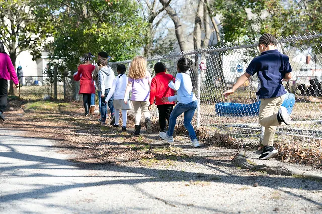 Children walking together along a fence on a nature walk